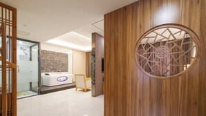 A reception area with a wooden panel, a reception desk, and a glass partition. - Riyue Lake Culture Hotel (Shangqiu)
