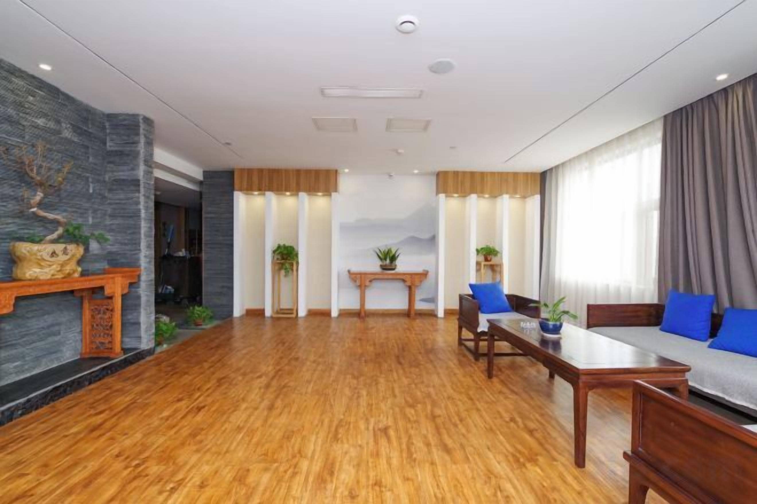 Un espacio amplio con piso de madera, un sofá con cojines azules, una mesa de comedor y una chimenea con adornos.