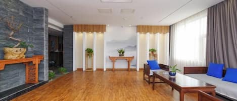 Un espacio amplio con piso de madera, un sofá con cojines azules, una mesa de comedor y una chimenea con adornos.