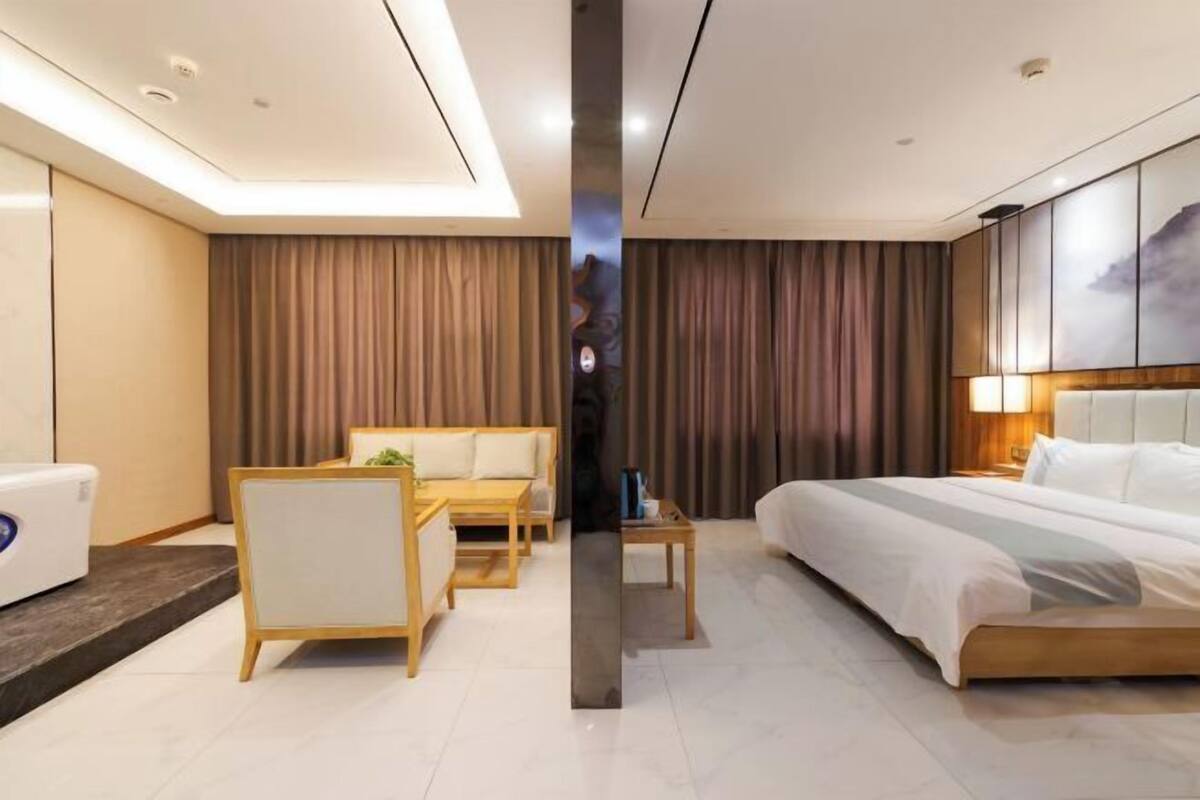 A modern hotel room with a bed, a sofa, a desk, and a chair.