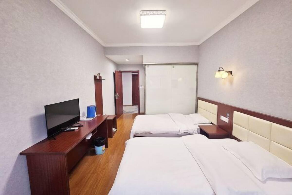 Hotellihuone, jossa on kaksi sänkyä, televisio, työpöytä ja vaatekaappi.