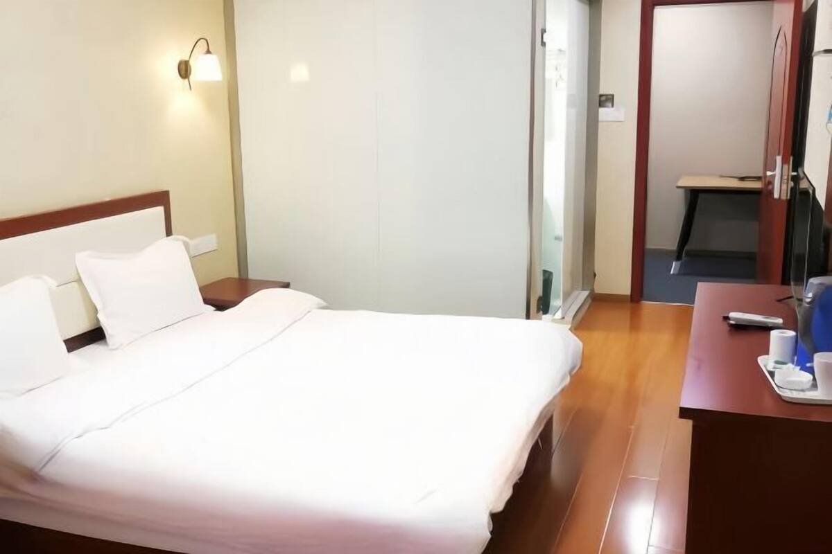 Hotellihuone, jossa on sänky, työpöytä, tuoli, lamppu ja peili.