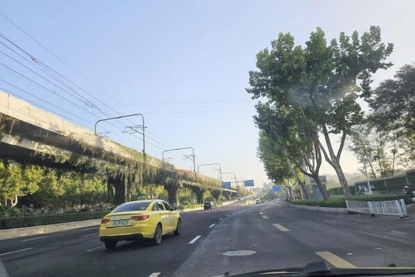 Une route avec un taxi jaune, un pont piétonnier et des arbres.