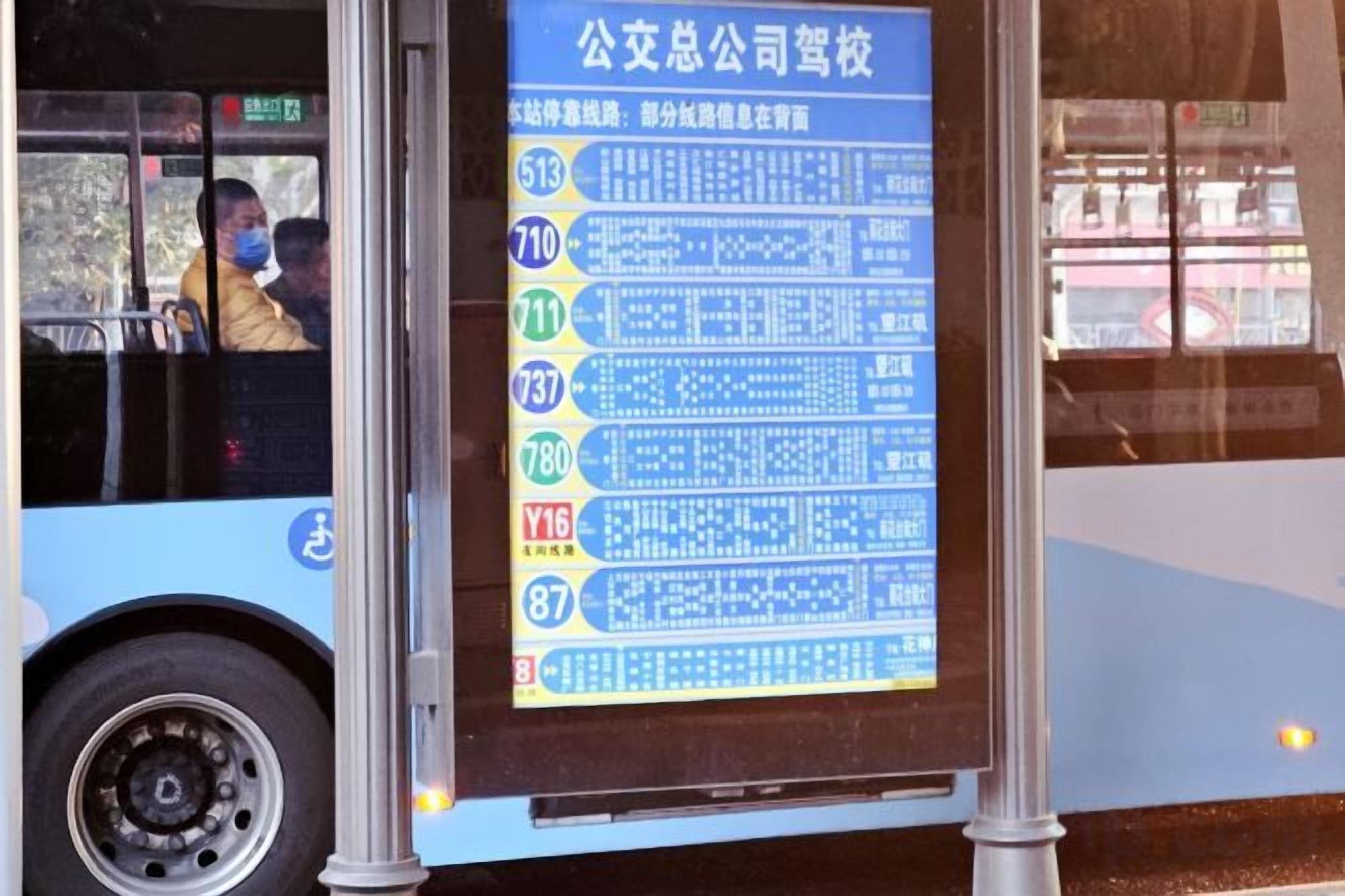 A bus with a large blue and white sign displaying bus route numbers and destinations.