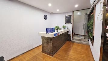 A reception desk with a clock, a menu board, and a plant.
