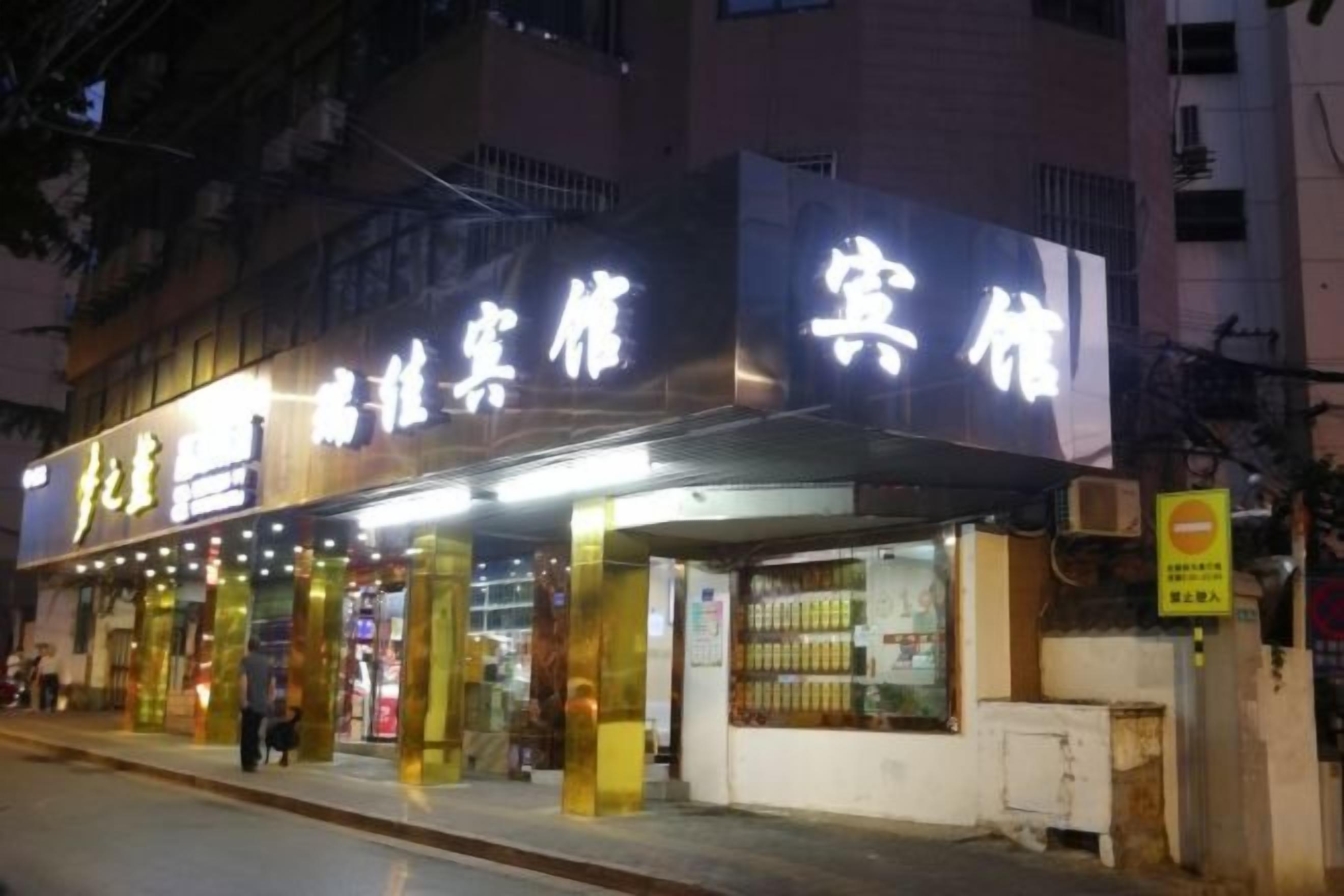 A hotel with illuminated signage, a covered entrance, and a visible storefront.