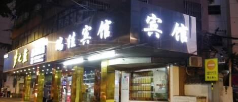 Un hotel con letreros iluminados, un acceso cubierto y un escaparate visible.