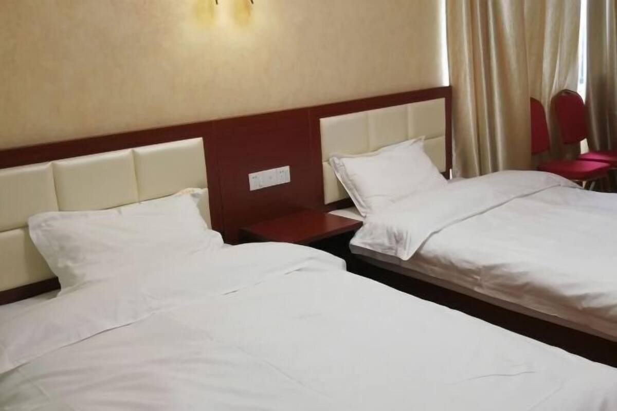 Hotellihuone, jossa on kaksi sänkyä, yöpöytä ja punainen tuoli.