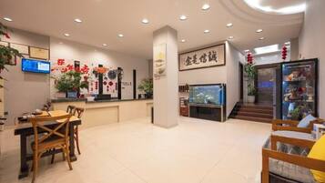 A hotel lobby with a reception desk, seating area, and a fish tank.