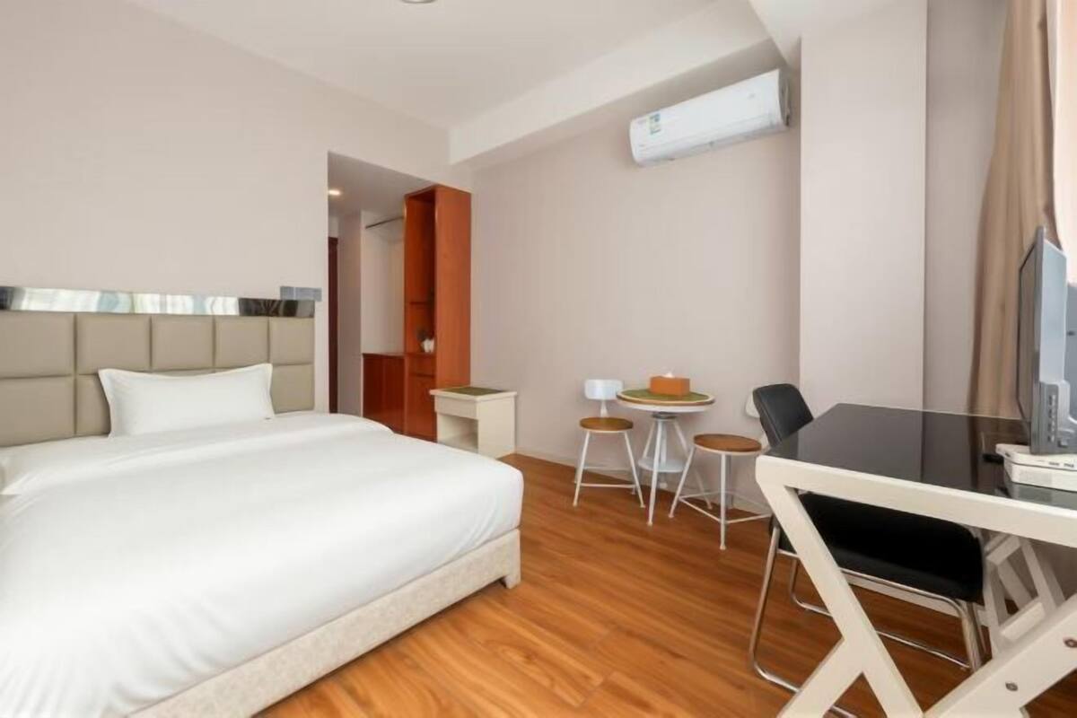 Une chambre d’hôtel équipée d’un lit, d’un bureau, d’une chaise, d’une petite table et d’un appareil de climatisation.