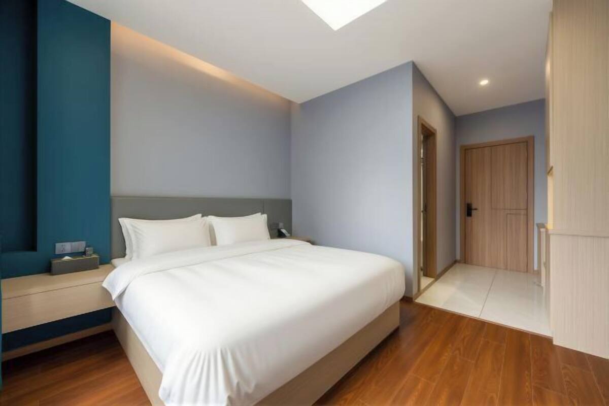 Une chambre à coucher avec un lit, une table de chevet et une porte donnant sur une autre pièce.