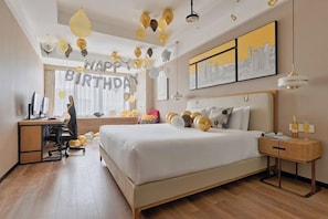 Quarto de hotel com uma cama grande, uma escrivaninha, uma cadeira e vista para a cidade.