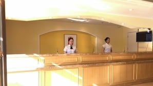 Ein Empfangsbereich mit einer Holztresen, einem gerahmten Bild an der Wand und einem Fernseher, der über dem Tresen angebracht ist.