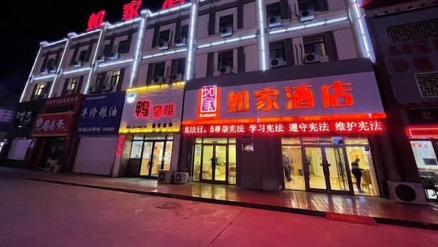 Ein Hotel mit beleuchteter Beschilderung, mehreren Stockwerken und einer Reihe von Geschäften im Erdgeschoss.