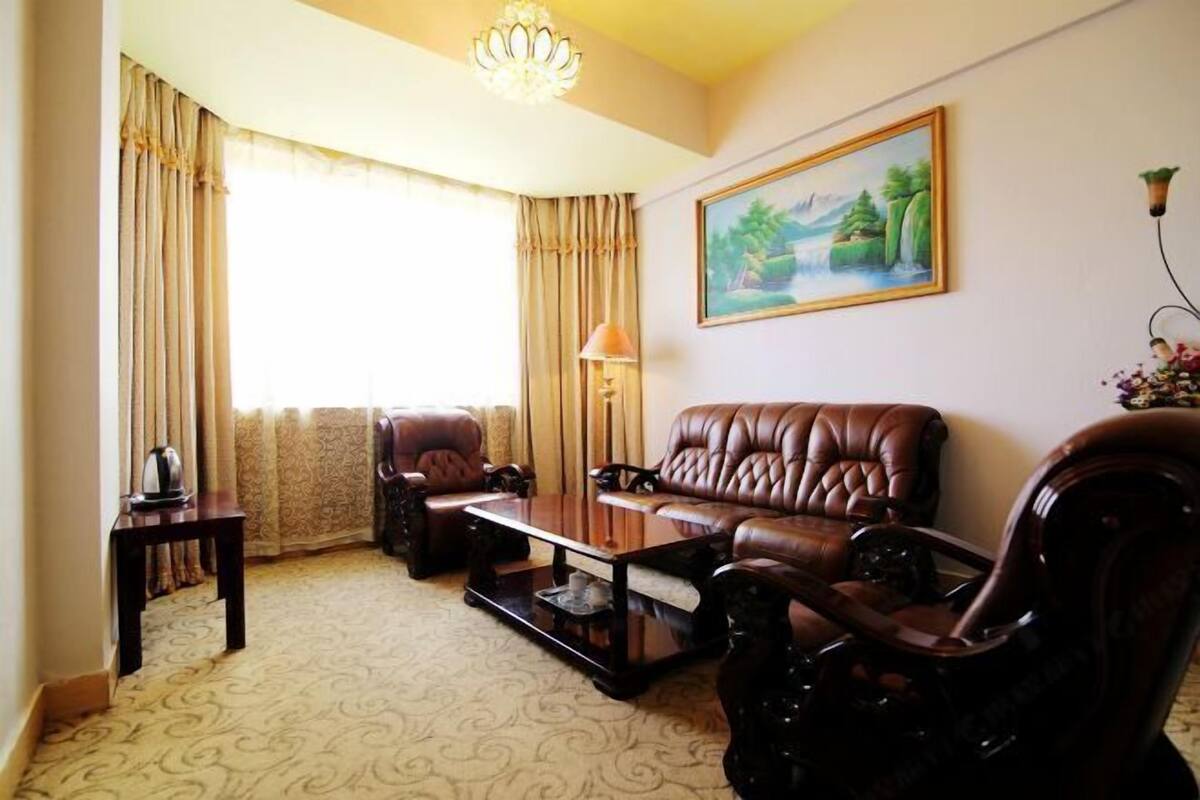 A living room with a sofa, armchairs, a coffee table, a lamp, and a painting on the wall.