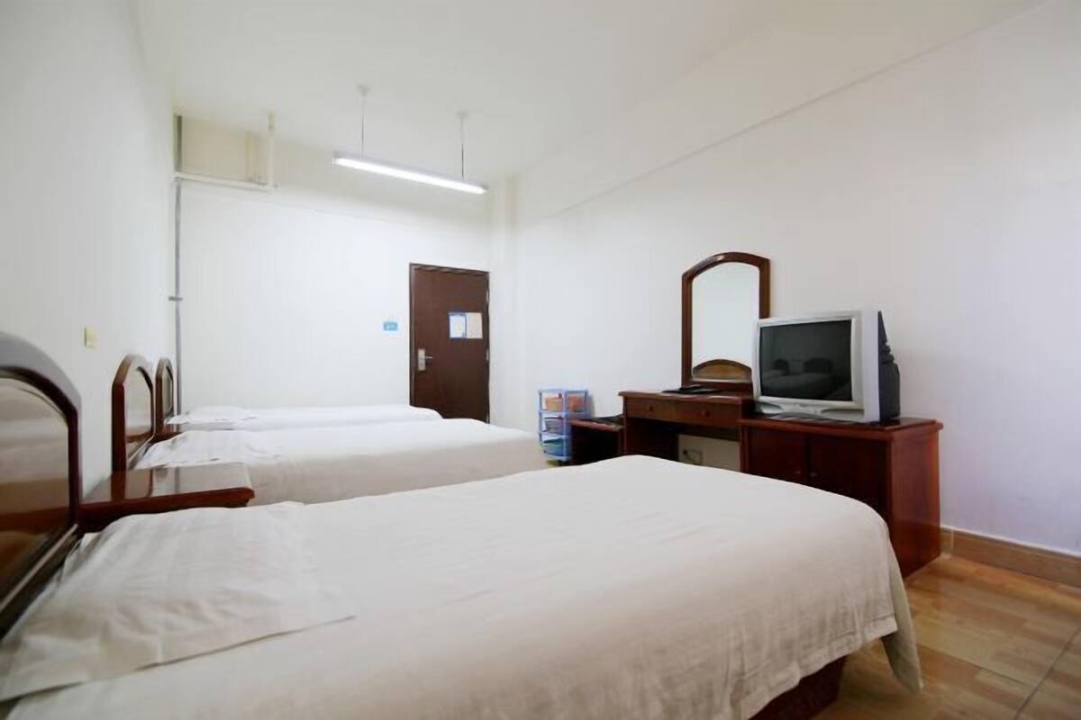A hotel room with two beds, a television, a desk, and a mirror.
