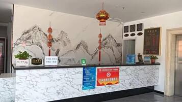 Un comptoir d’accueil avec un plateau en marbre, une fresque murale et une lanterne suspendue.