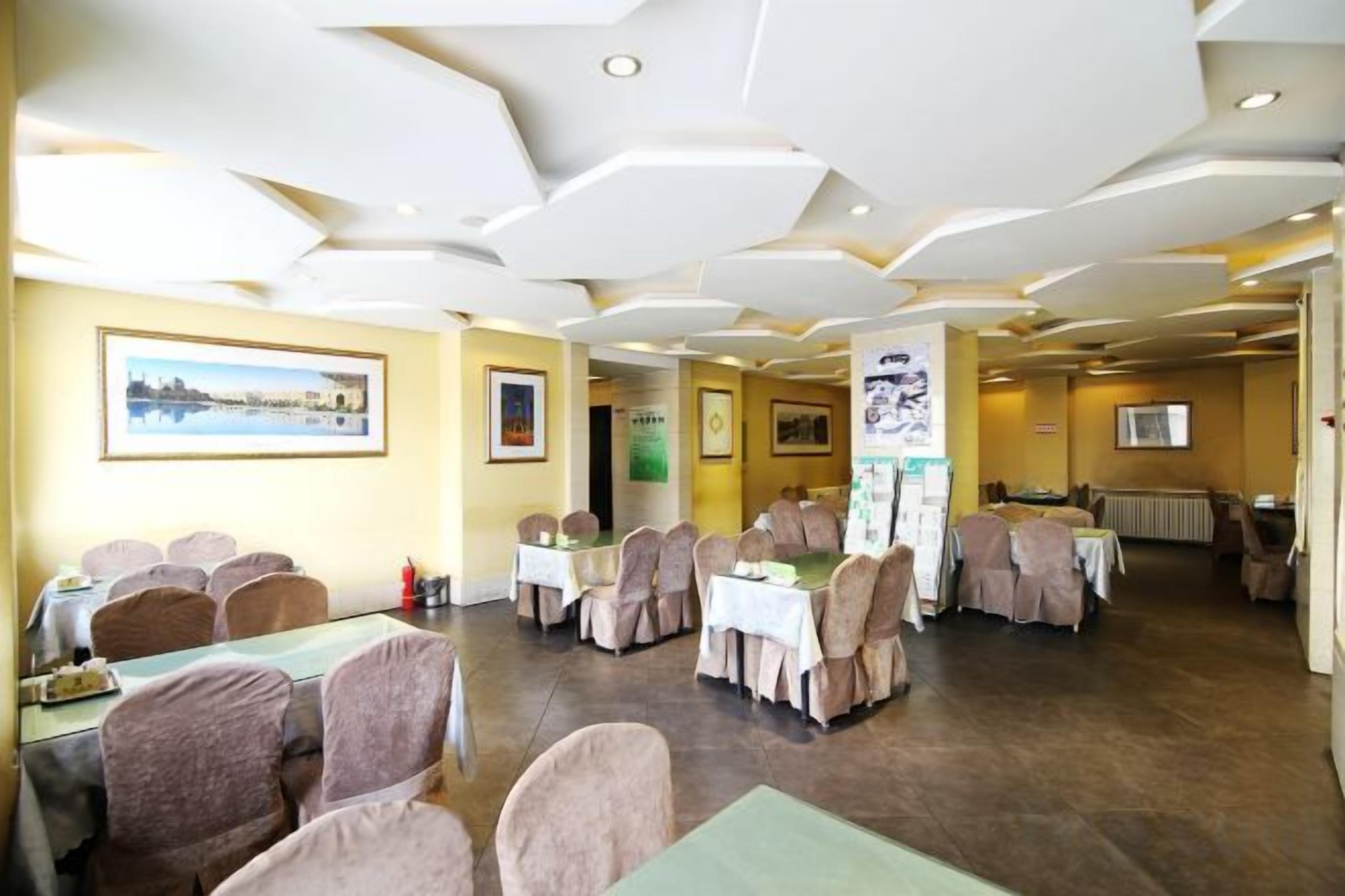 A conference room with round tables, chairs, and a white ceiling with recessed lighting.