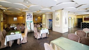 Un restaurante con mesas, sillas, un cartel de menú y decoración en la pared.