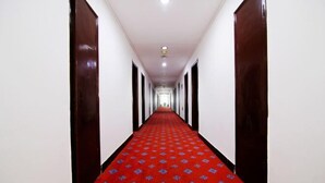 Un pasillo largo y estrecho con alfombra roja y paredes blancas.