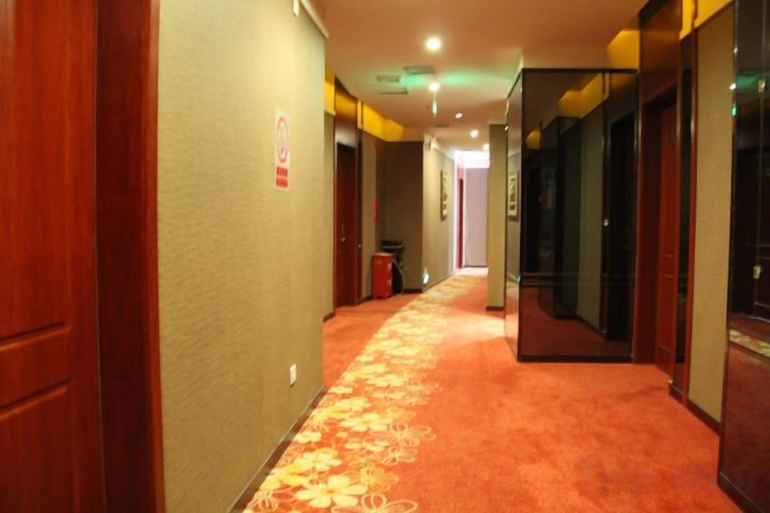 Un pasillo de hotel con piso alfombrado, puertas a ambos lados y un basurero en el centro.