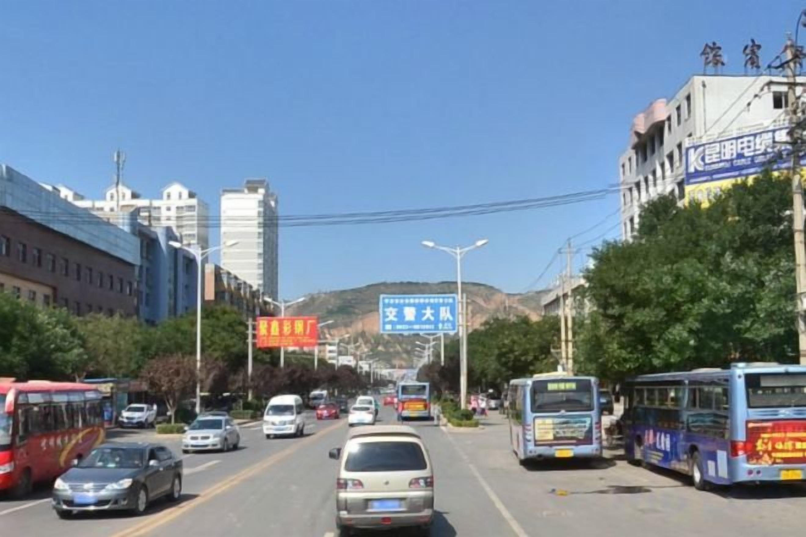 Una carretera con varios carriles, con vehículos, incluyendo autobuses y automóviles, y edificios a ambos lados.