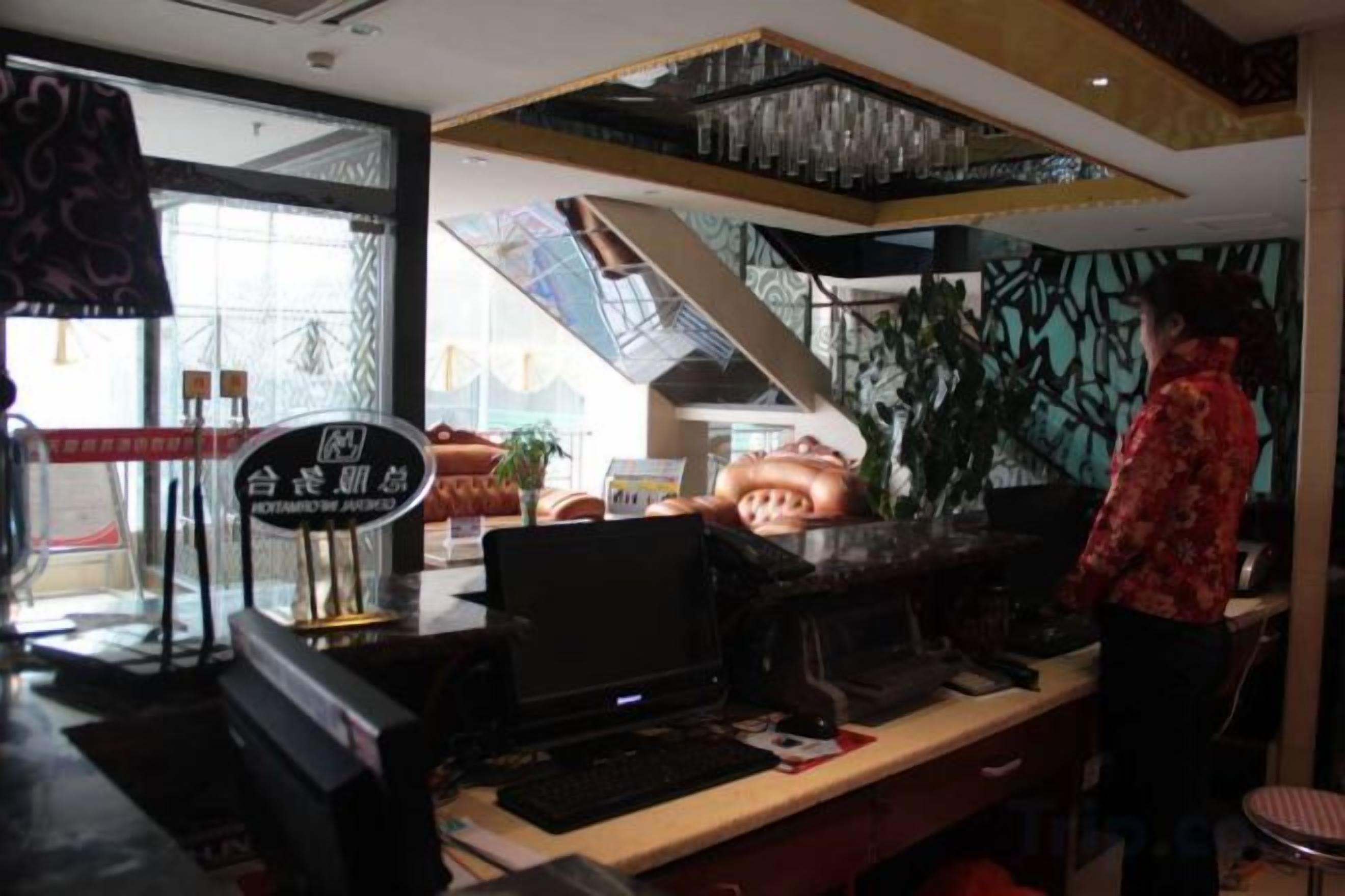 L’intérieur d’un restaurant avec un comptoir, un ordinateur et une personne debout.