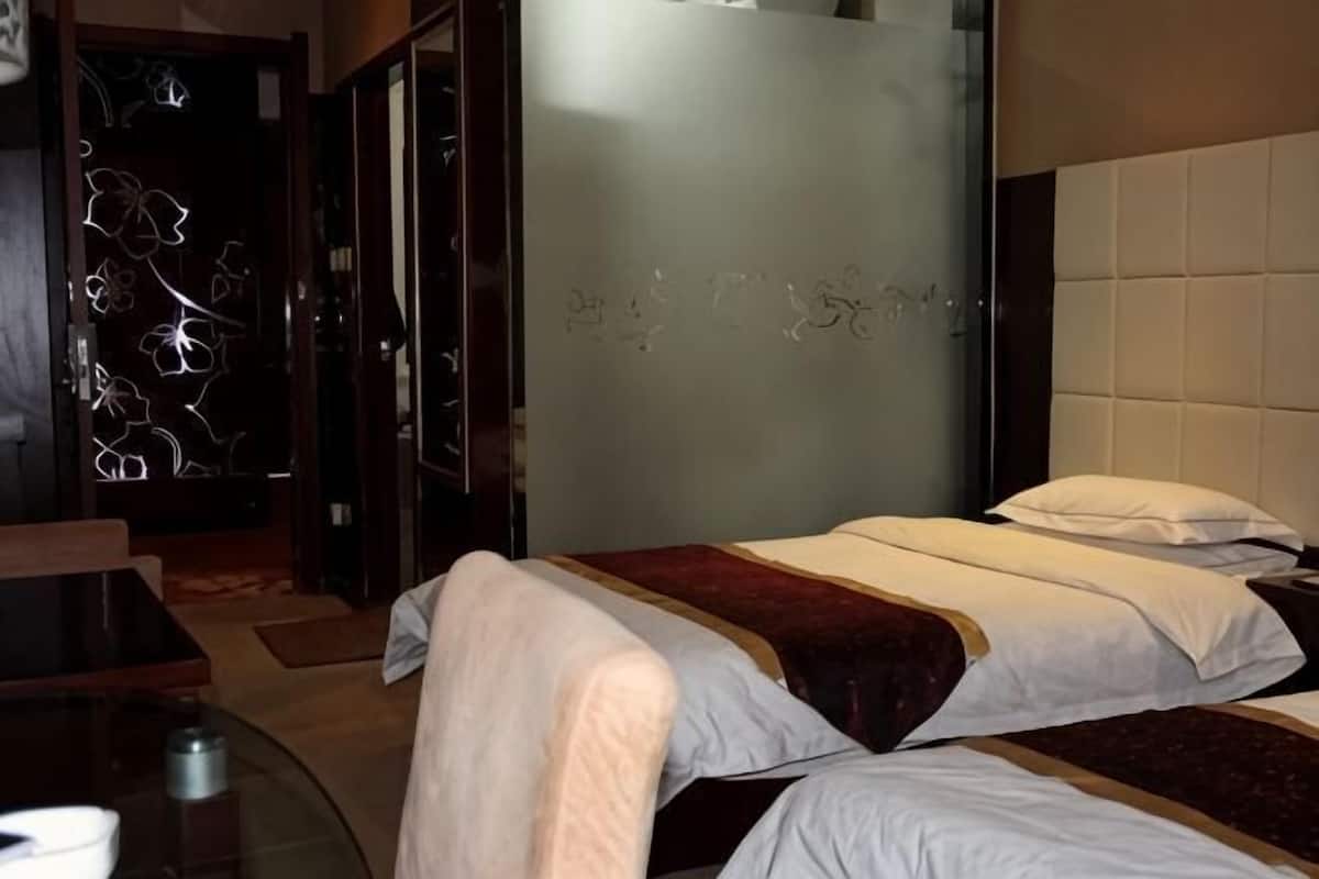 A hotel room with two beds, a glass door, and a wall with graffiti.