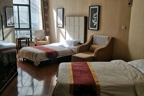 Ein Hotelzimmer mit zwei Betten, einem Sofa, einem Sessel und einem kleinen Tisch.