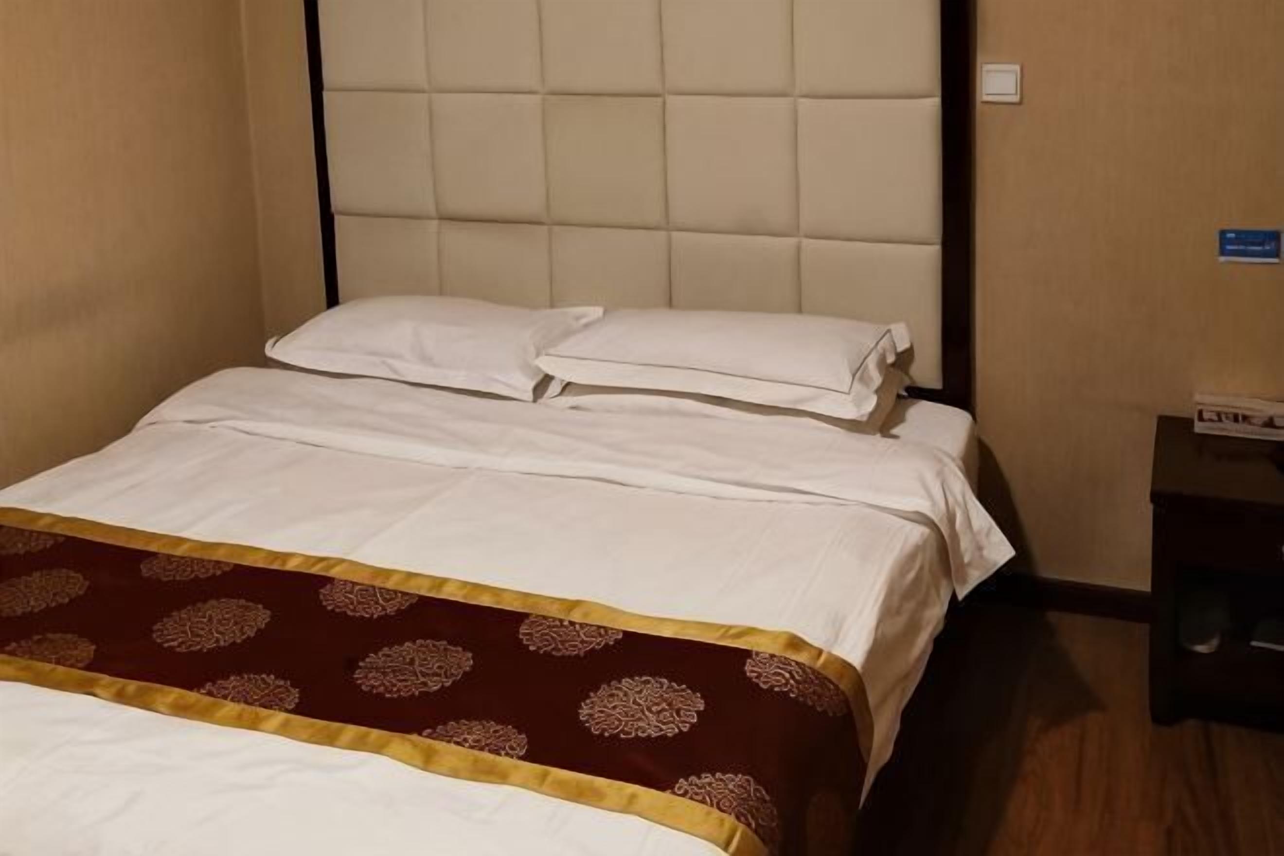 A hotel room with a bed, a nightstand, and a sign on the wall.