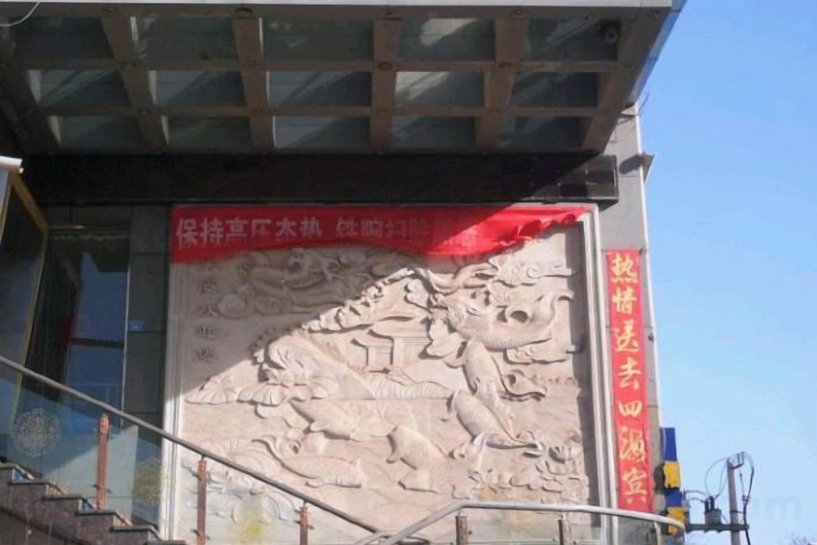 A building facade with a large relief sculpture and a red banner with Chinese characters.