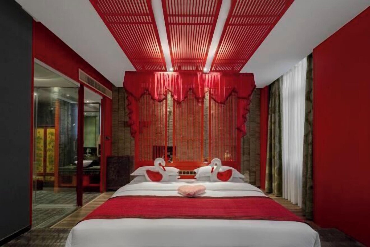 Una habitación de hotel con una cama grande, cortinas rojas y un diseño de techo rojo.