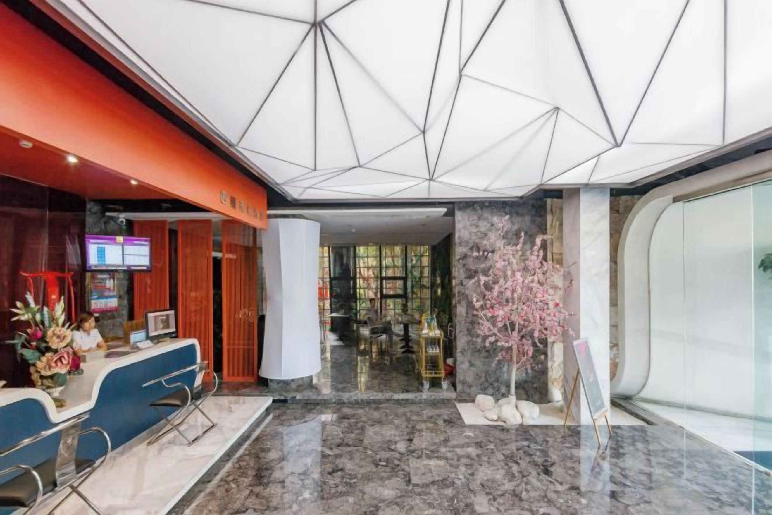 Un vestíbulo de hotel con mostrador de recepción, zona de estar y un amplio ventanal.