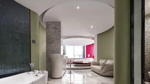 A modern bathroom with a large bathtub, a round seating area, and a red accent wall. - Mianyang 4D Future Hotel (Gaoshui Branch) (Mianyang)