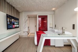 A modern hotel room with a glass desk, a bed with red bedding, a television mounted on the wall, and a red door leading to another room. - Mianyang 4D Future Hotel (Gaoshui Branch) (Mianyang)