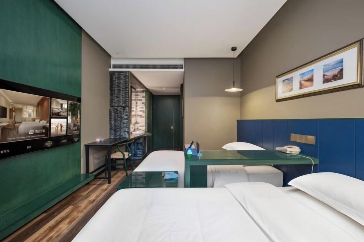 Una habitación de hotel con una cama, un escritorio, una silla, un televisor y un espejo.