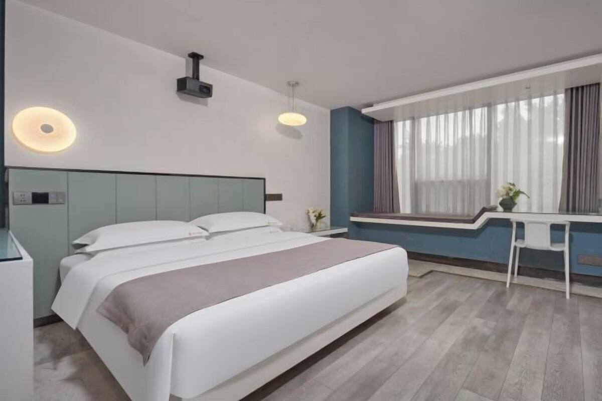 Ein modernes Hotelzimmer mit Bett, Nachttisch und einem Vorhangfenster.