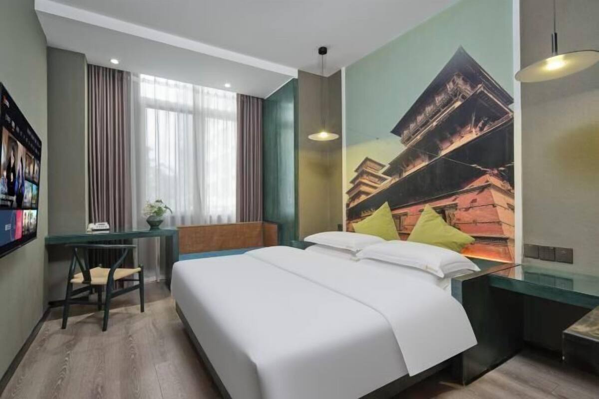 Ein Hotelzimmer mit einem Bett, einem Schreibtisch, einem Stuhl und einem großen Fenster mit Vorhängen.