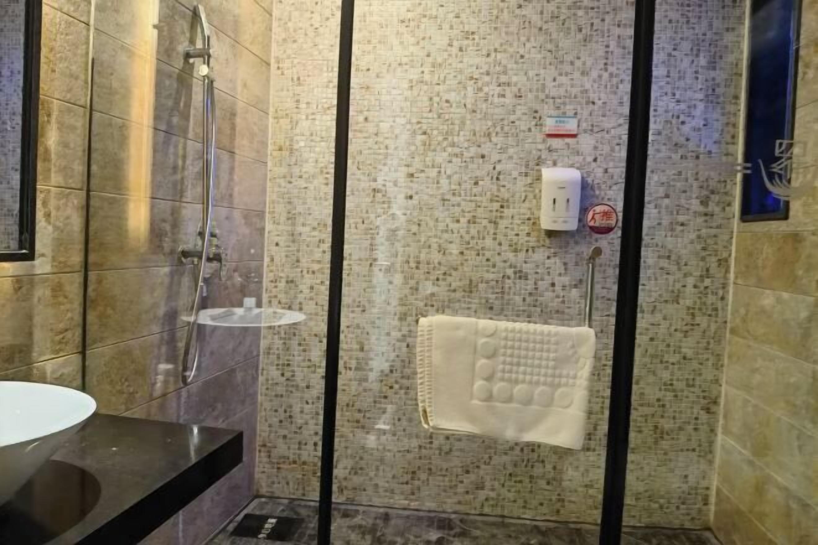 A bathroom with a glass shower enclosure, a towel rack, and a sink.