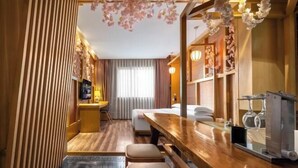 A hotel room with a wooden floor, a wooden desk, a bed, and a seating area with stools. - Mianyang 4D Future Hotel (Gaoshui Branch) (Mianyang)