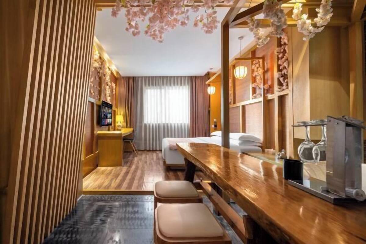 Ein Hotelzimmer mit Holzboden, einem Holztisch, einem Bett und einer Sitzecke mit Hocker.