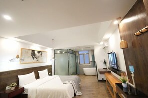 Et moderne hotelværelse med seng, fjernsyn, badekar og bænk i træ.
