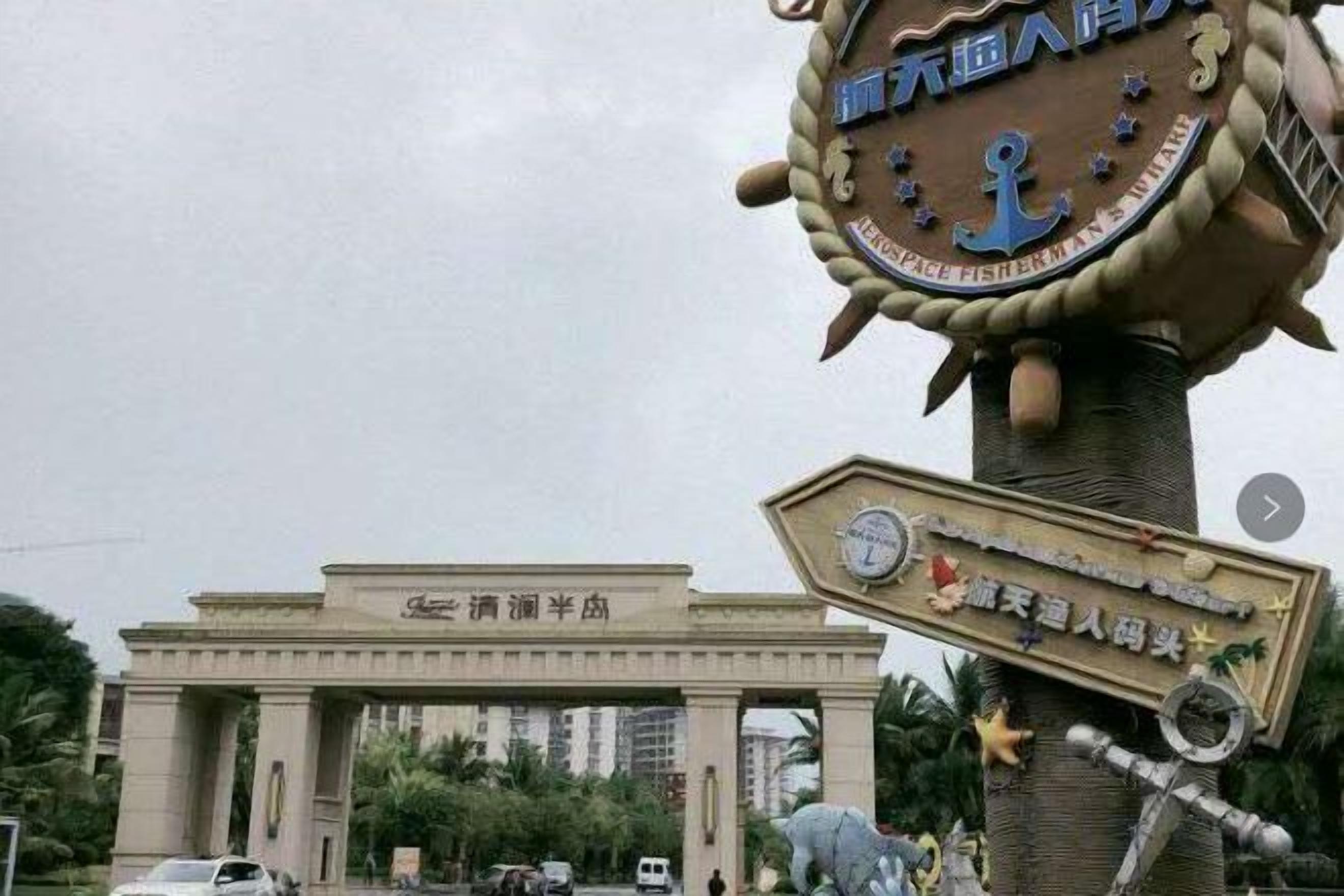 A large archway with a sign above it, and a tall structure with a sign on top.
