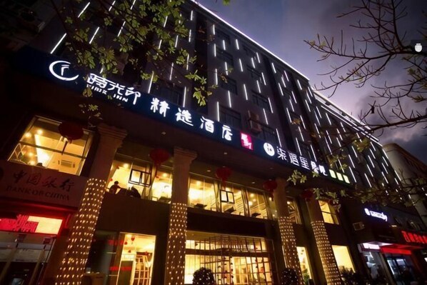 Um hotel com fachada moderna, sinalização iluminada e entrada destacada.