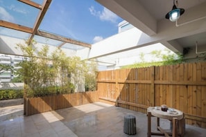 An outdoor patio with a wooden fence, a table, and a hanging light fixture. - Time Inn (Wenchang)