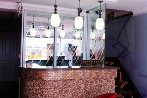 Uma área de recepção com balcão revestido de azulejos, luminárias pendentes e um espelho refletindo o interior.