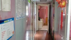 A hallway with glass doors, a bulletin board with notices, and a red decorative item. - Xingsheng Hostel (Shanghai)