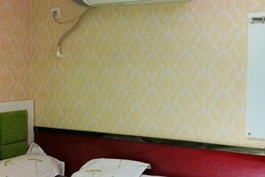 Quarto com parede estampada, cabeceira vermelha e ar condicionado branco.