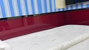 A hotel room with a bed, a TV mounted on the wall, and a striped wall. - Xingsheng Hostel (Shanghai)