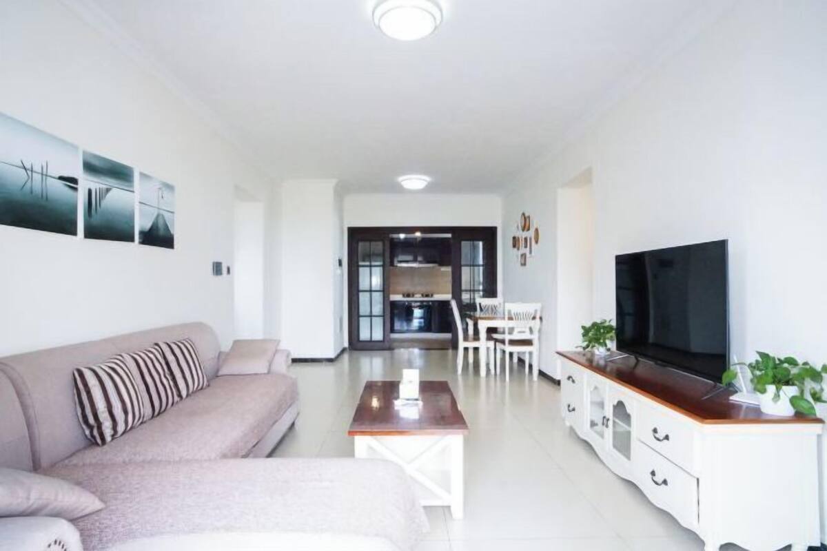 A modern living room with a sofa, coffee table, TV, and cabinets.